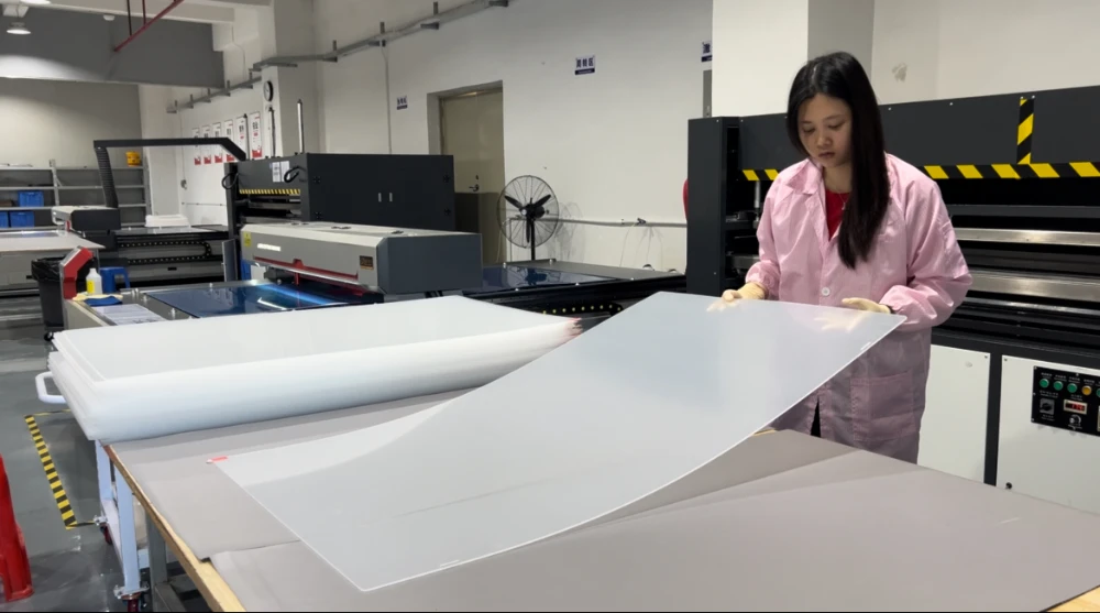 Factory worker inspecting a large transparent acrylic TV screen protector for clarity and surface defects