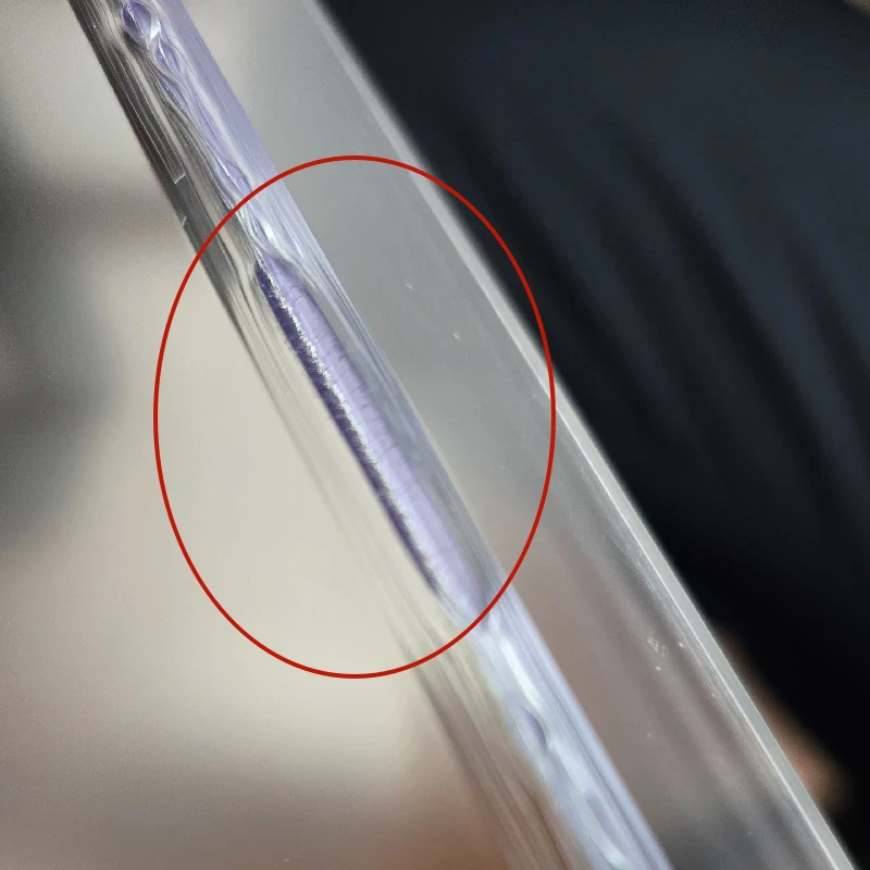 A close-up photograph of an acrylic panel corner showing visible stress cracks and fissures along the curved edge, resulting from a suboptimal heat-bending process, typical of inferior craftsmanship