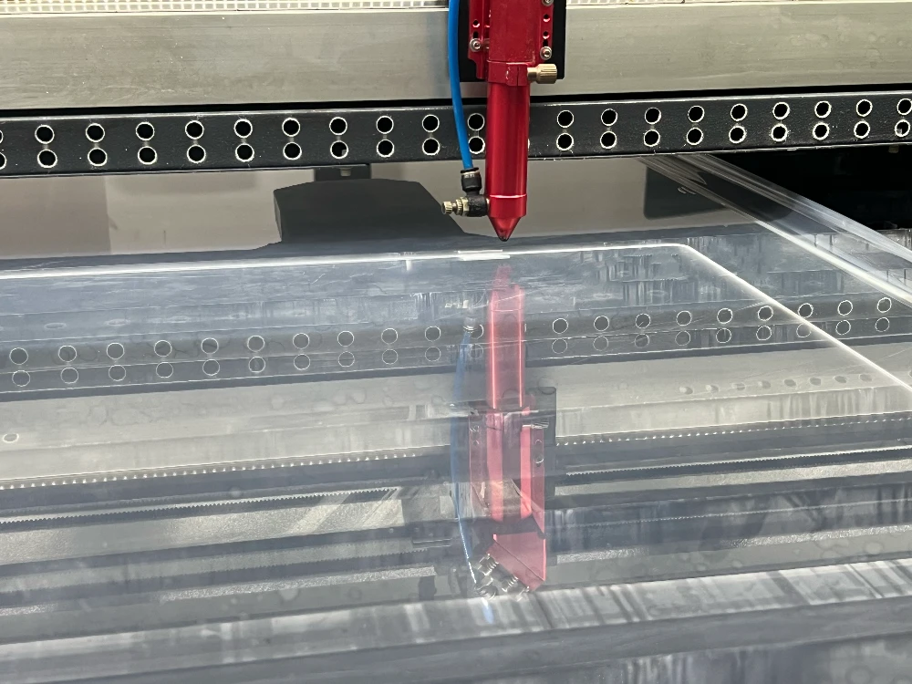 High-precision laser cutting machine processing a clear acrylic TV screen protector panel in the factory